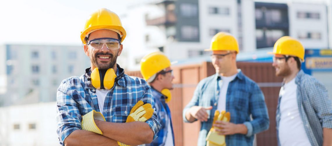 33301060 - business, building, teamwork and people concept - group of smiling builders in hardhats outdoors