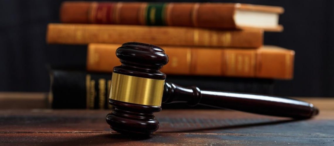 Law gavel on a wooden desk, law books background